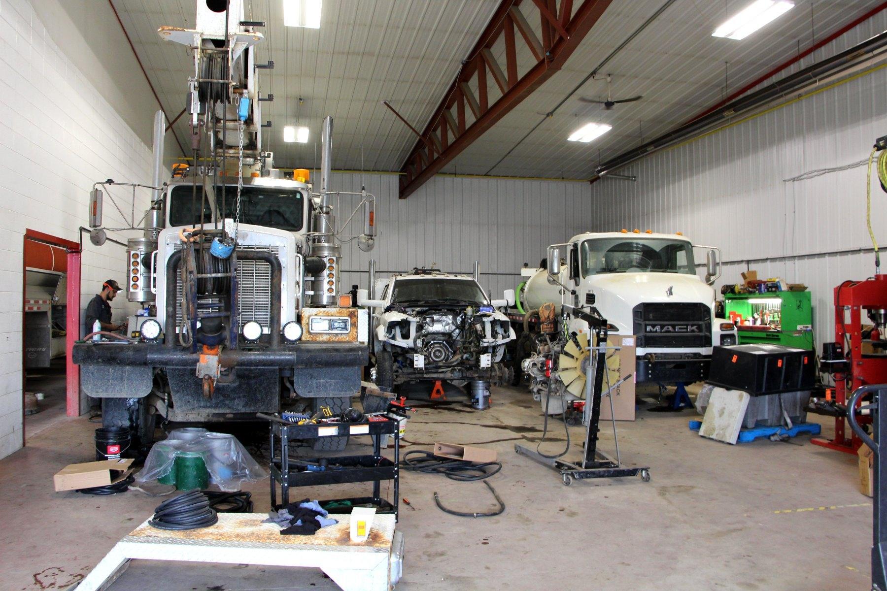 Inside the Big Horn Industries shop: a crane truck, a pickup with its engine bay open and a Mack truck in the service bays.